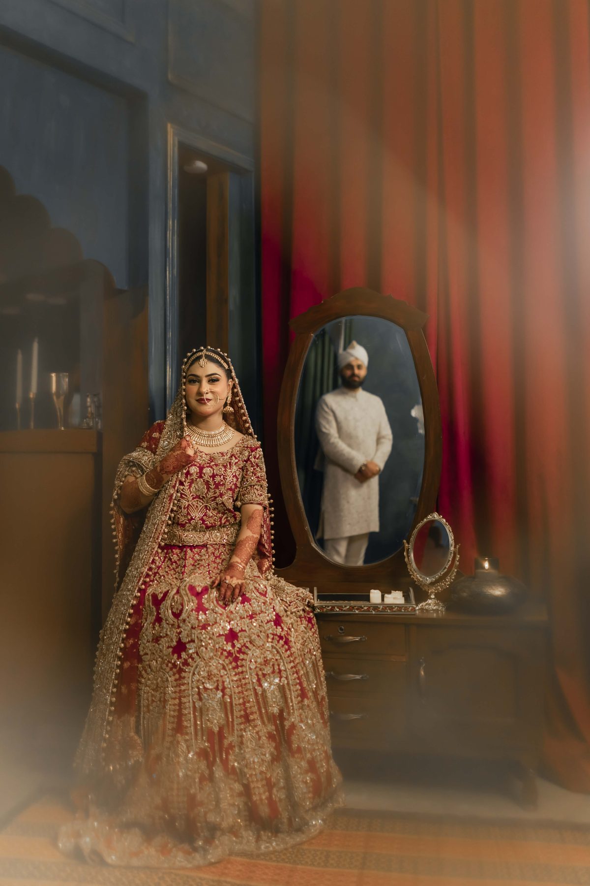 Bride in red bridal lehenga reflected in an antique mirror set