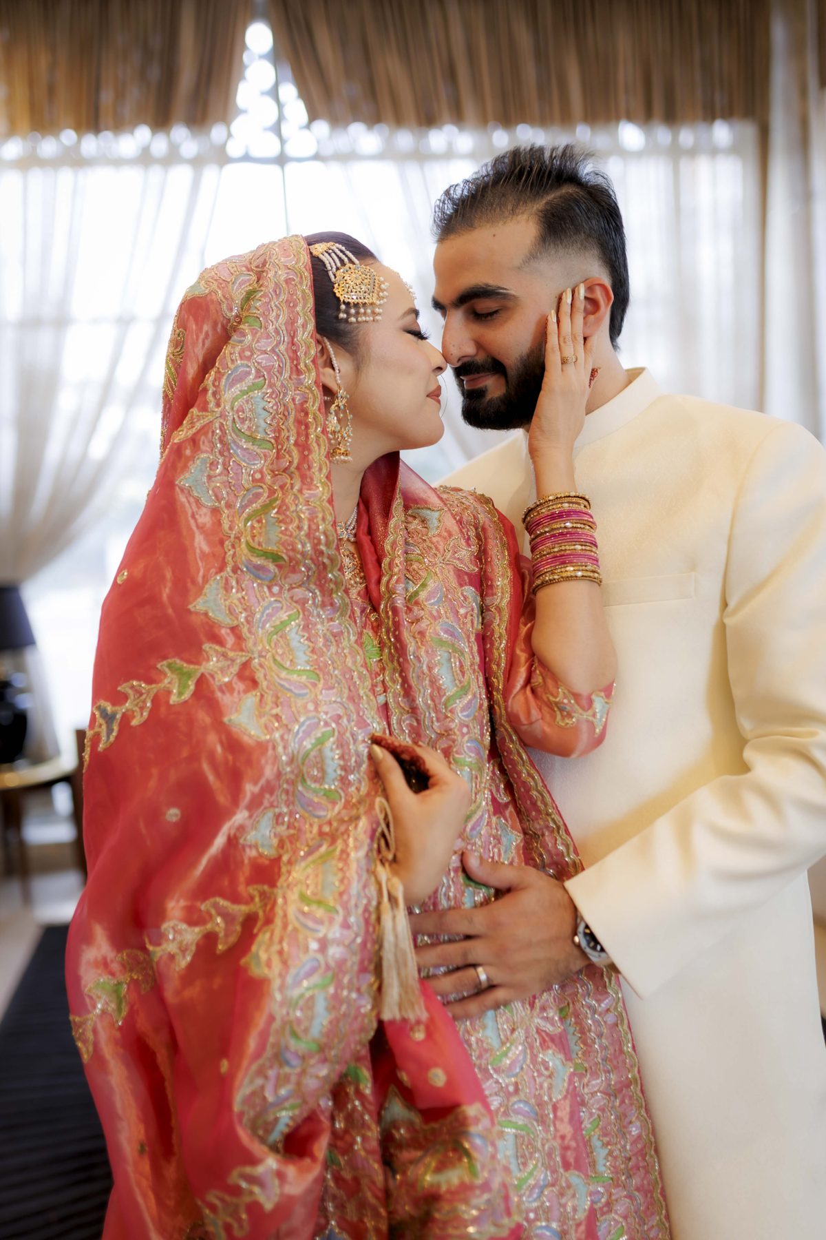 Nikah couple in red and ivory sharing an intimate moment