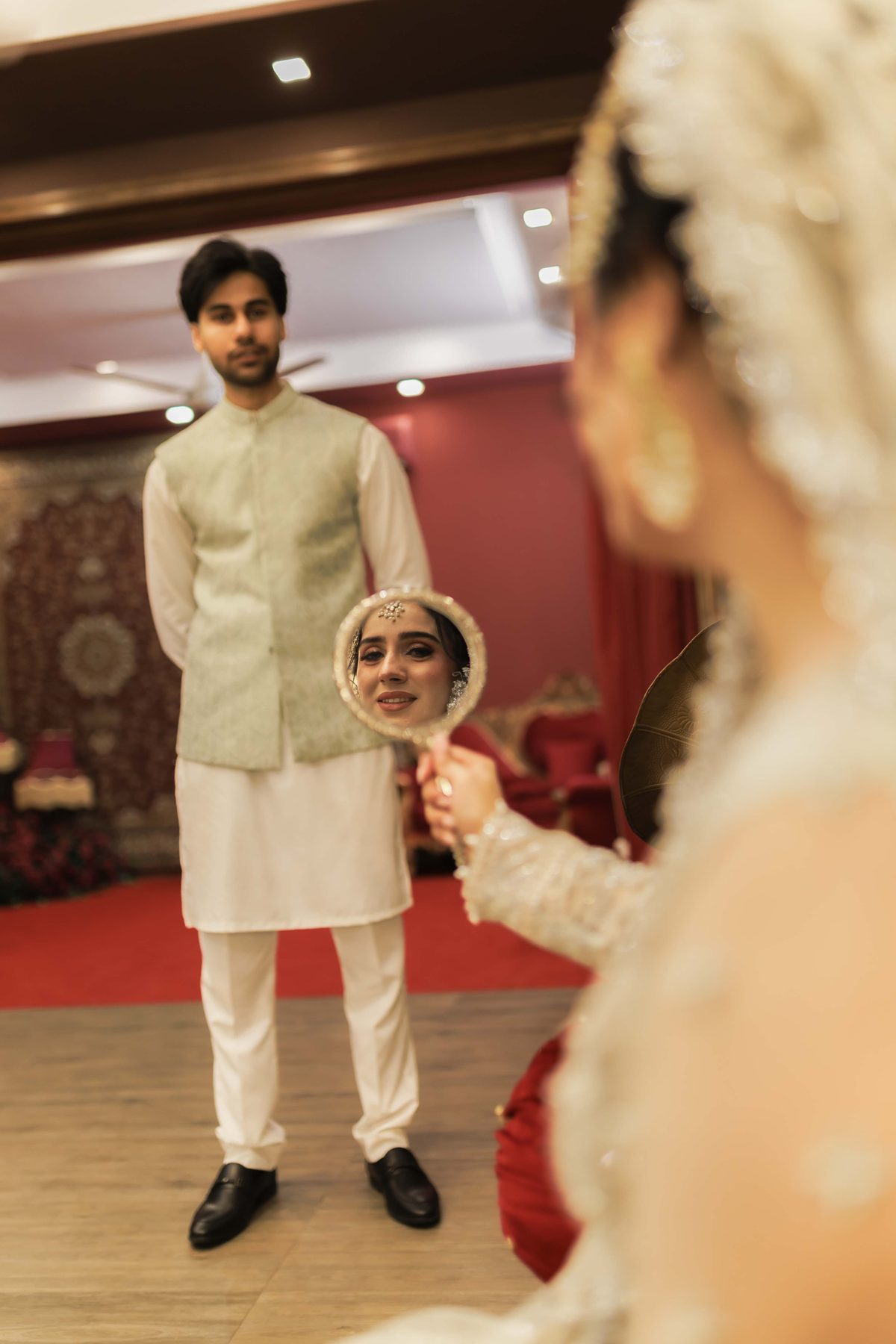 Pakistani groom in ivory sherwani lifting his bride’s veil at a Lahore wedding