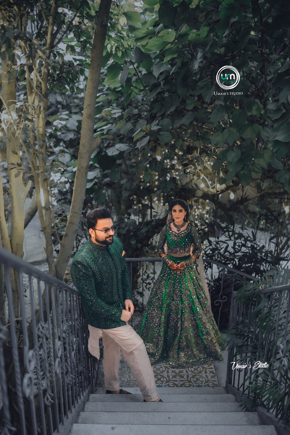 Couple in emerald green outfits on a heritage staircase